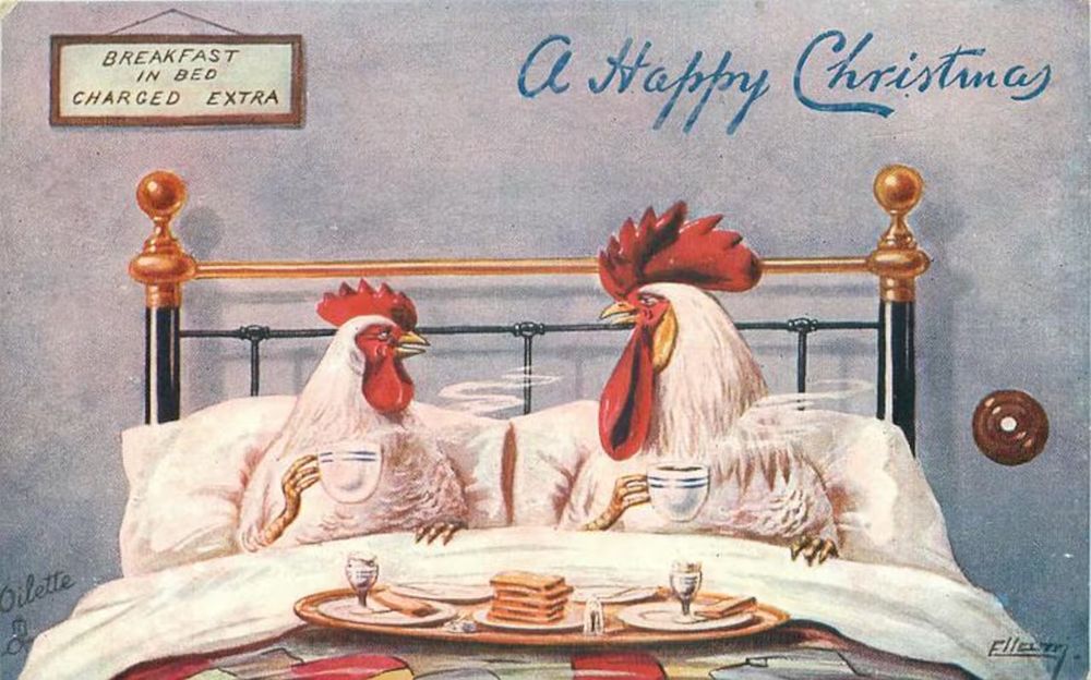 A 1908 Christmas postcard showing a white rooster and hen in a hotel bed each holding a coffee cup. A sign says breakfast in bed charged extra. The card text says O Happy Christmas in script. There is a breakfast tray on the bed with a stack of toast and two egg cups.