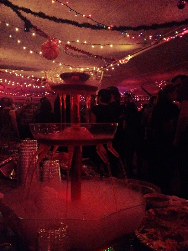 a holiday party with a plastic fountain full of dry ice and a red drink in the foreground