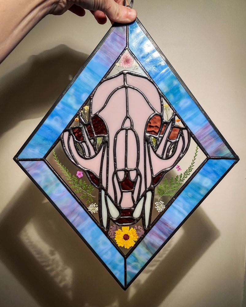 The same tiger skull stained glass piece, but lit from the front so the colors appear differently and a shadow is cast on the wall behind