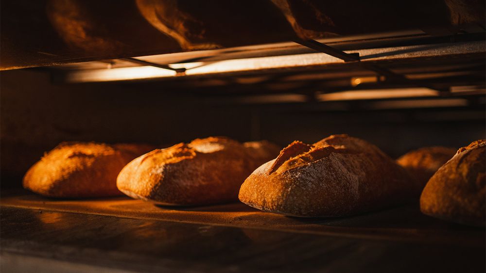 Loaves of bread baking in an oven, illuminated by warm light.