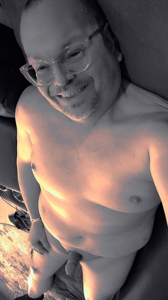 Naked man sitting in living room with a hard cock 