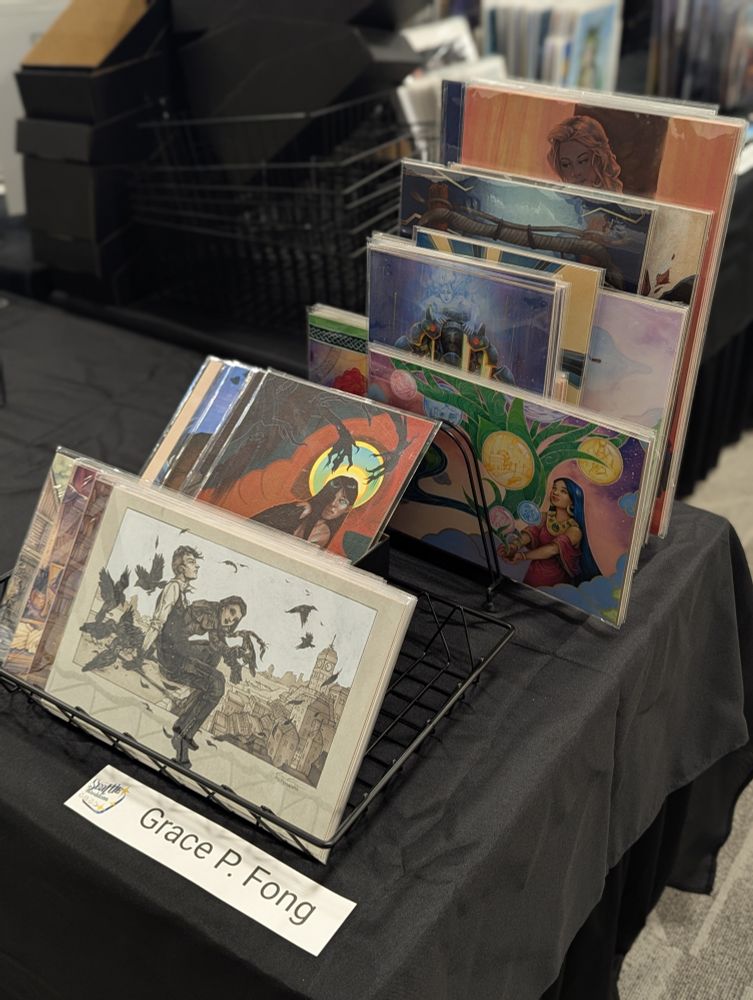 A display stand of prints by Grace P. Fong on sale at Worldcon 2025 in Seattle.