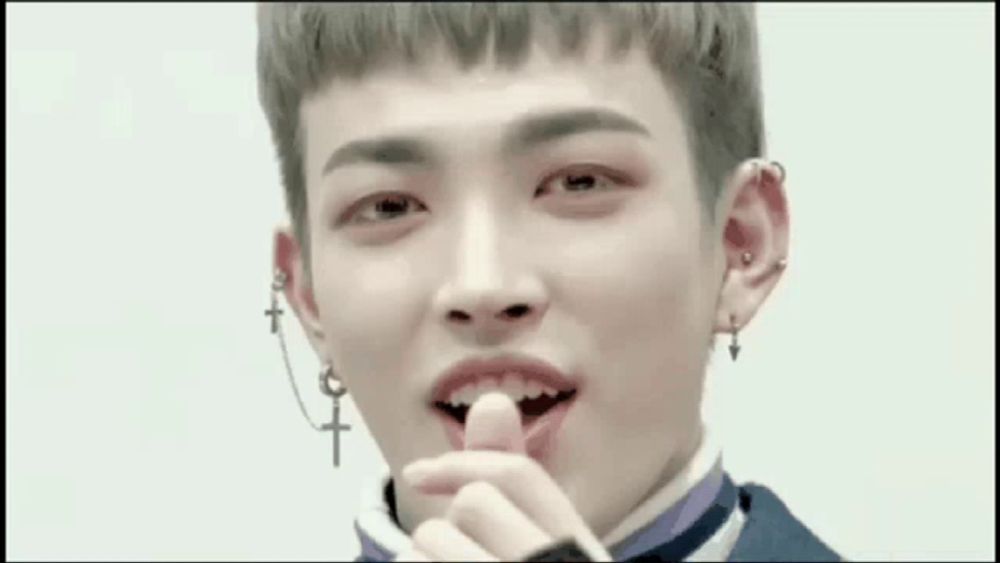 a close up of a young man wearing earrings and a cross piercing on his ear .