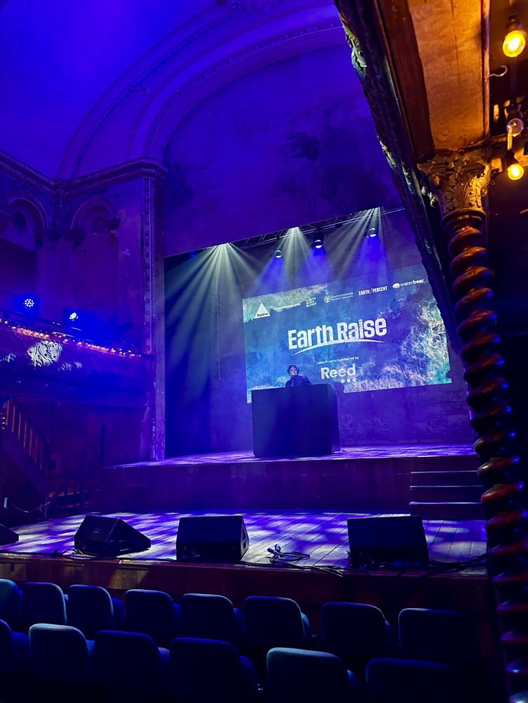 A DJ on stage with an image behind them saying ‘Earth Raise’.