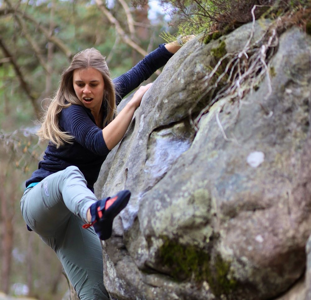 Emma climbing a boulder in the forests of Fontainebleau.