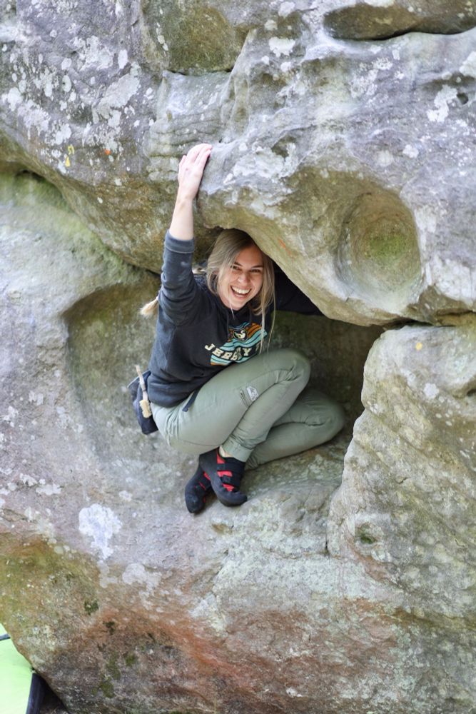 Emma standing in a hole part way up a bouldering route.