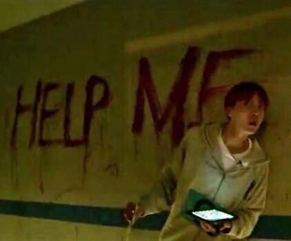 jung hoseok, also known as j-hope from the korean boy band bts, looking scared, confused and nervous. behind him is a wall saying “help me” in red.