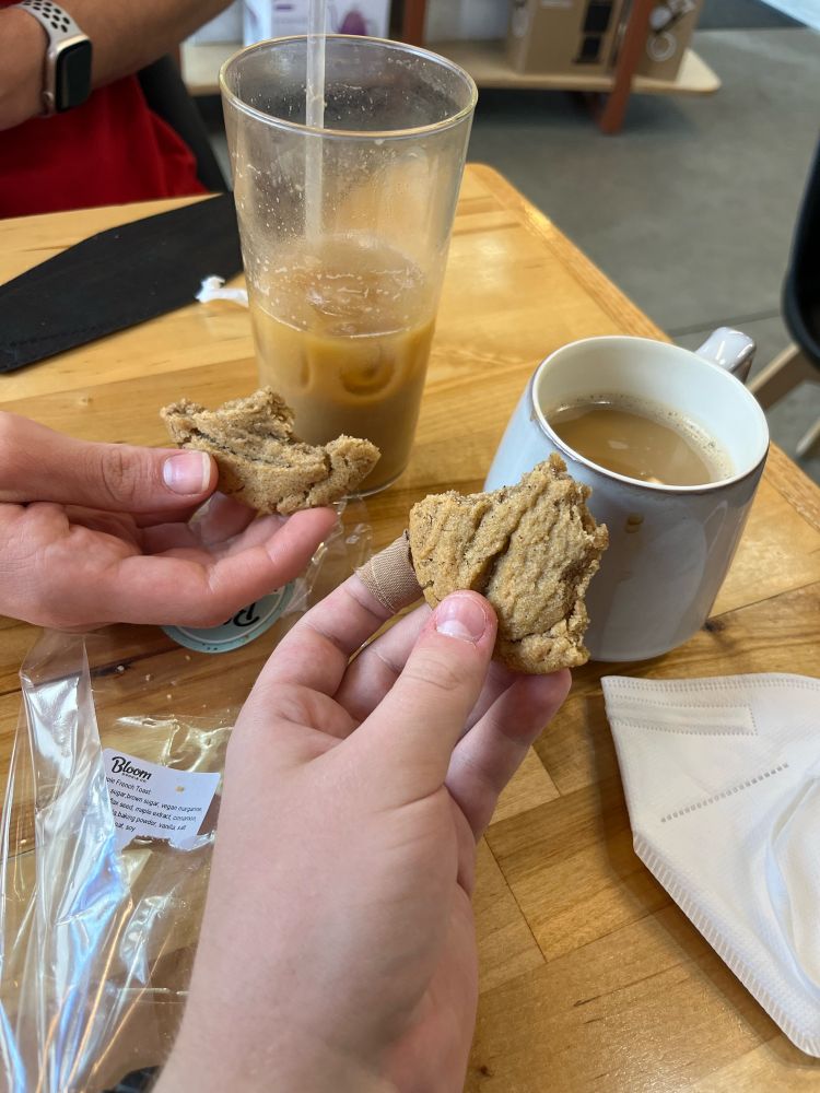 A picture of a hot coffee and an iced coffee next to each other, with each of us holding half eaten cookies next to our respective drinks.
