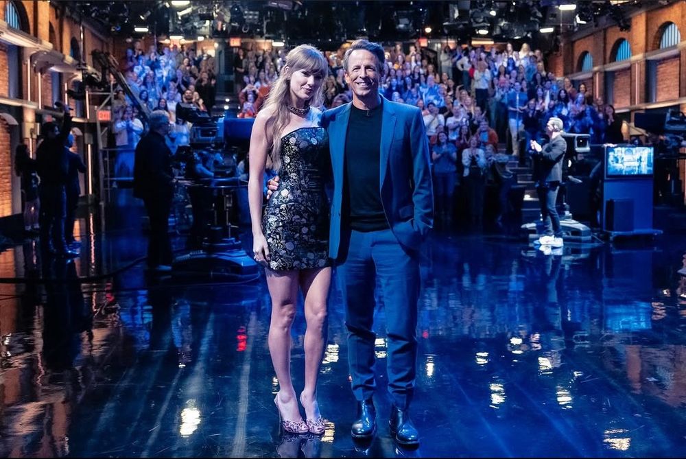 taylor swift and seth meyers posing for a picture together. the crowd is in the background. 