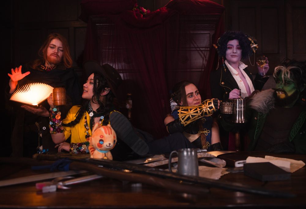 Caleb and Veth are sitting on the left talking. Beauregard, Kingsley and Fjord are talking and drinking on the right side of the table.