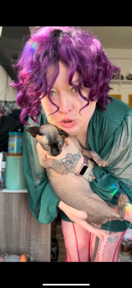 Op holds the sphinx fat up to the camera. His head is pressed against OP’s cheek in a kitty cuddle and OP is doing the baby talk face 