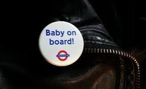 White badge on a leather jacket, blue text and a red and blue TfL rondel: Baby on board! 