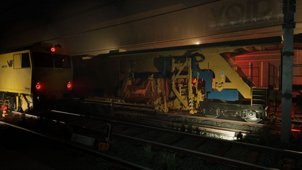The Image represents a night scene of a railway besides a station or warehouse entrance. The trains are lit by work lights in a yellow tint