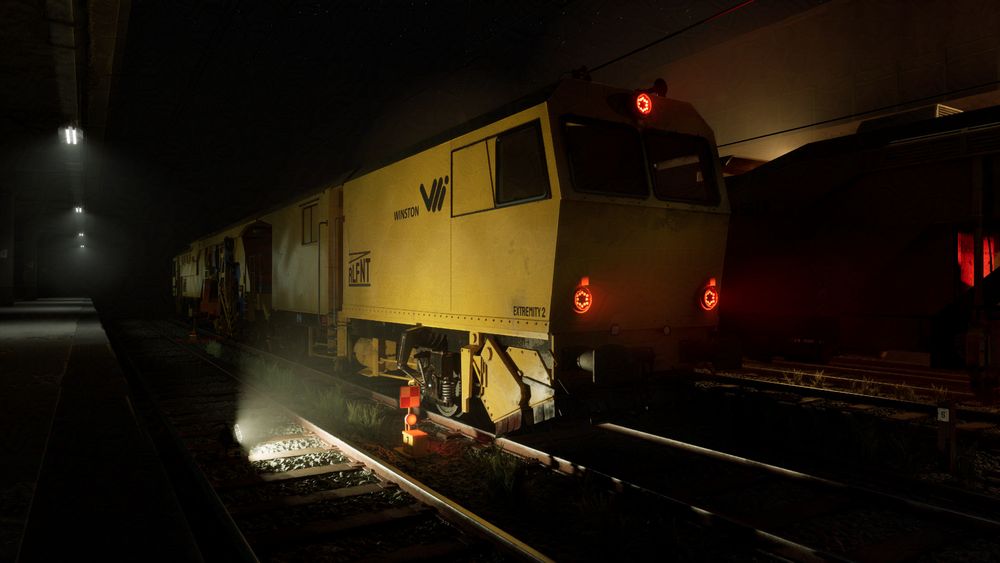The Image represents a night scene of a railway besides a station or warehouse entrance. The trains are lit by work lights in a yellow tint