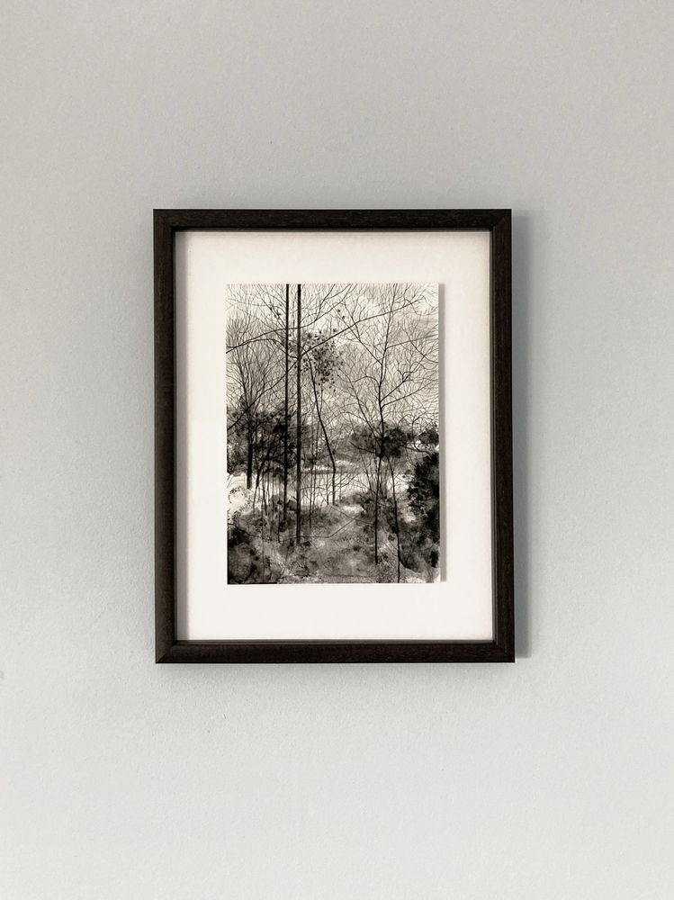 Framed black and white ink drawing of a woodland landscape. 