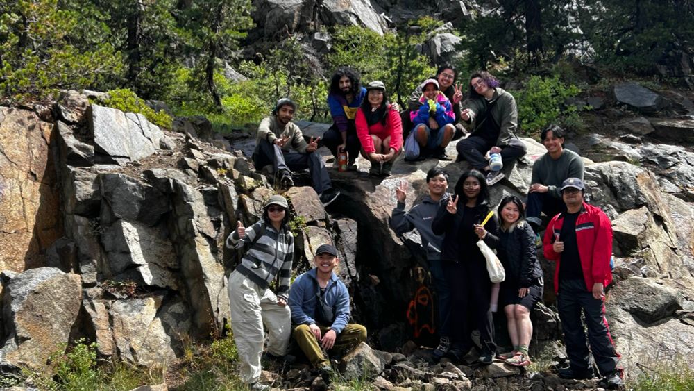 group of people standing in front of and on a bed of rocks 
