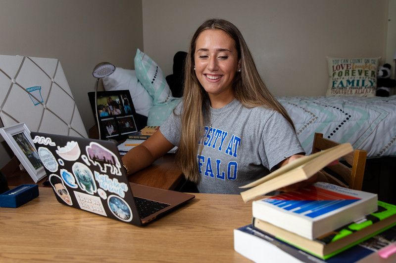 A University at Buffalo student sitting at her desk in a UB residence hall working on her laptop. 
