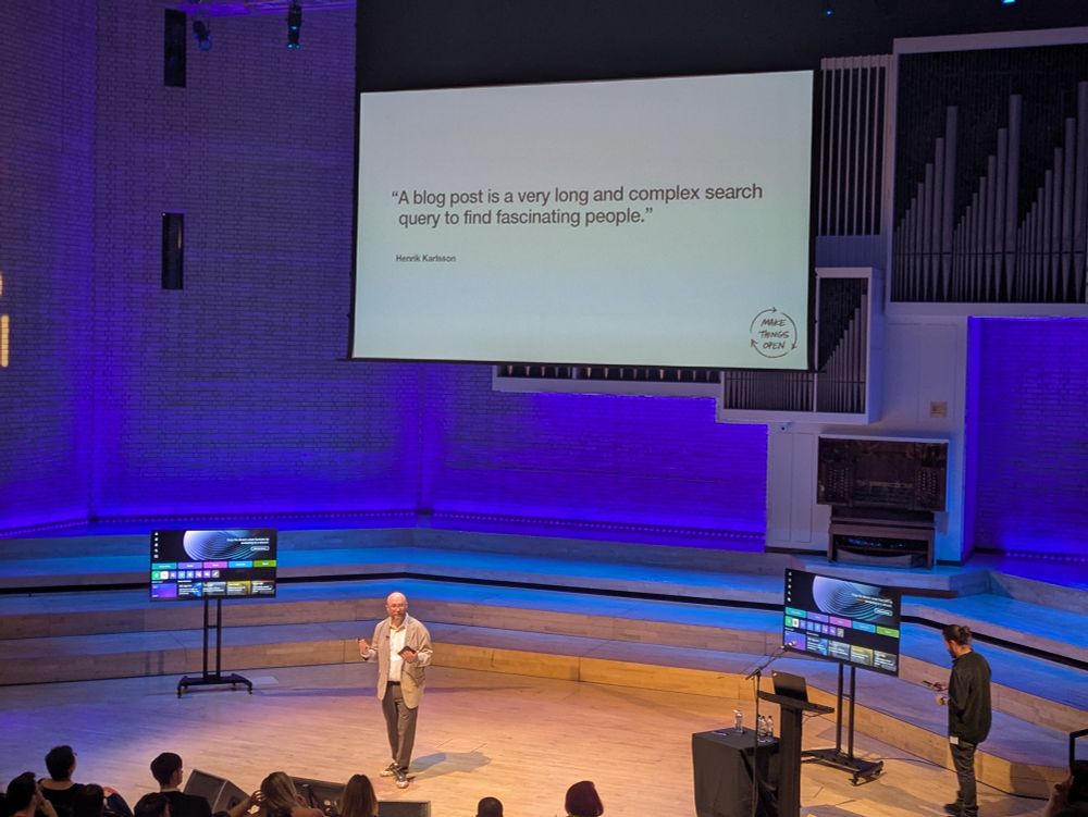 A white man on a conference stage, standing in front of a large screen on which are the words:

A blog post is a very long and complex search query to find fascinating people

Henrick Karlsson
