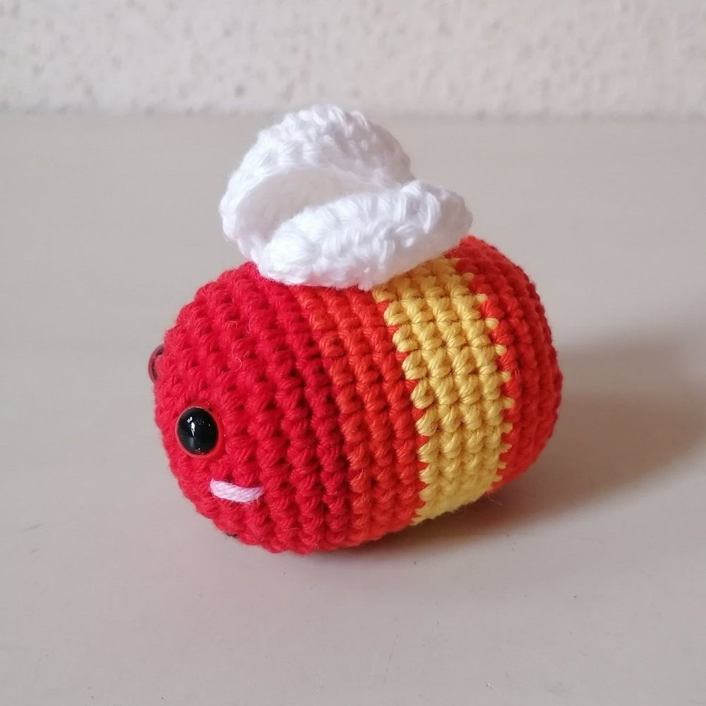 gehäkeltes Bienchen in rot, orange und gelb mit weißen Flügeln