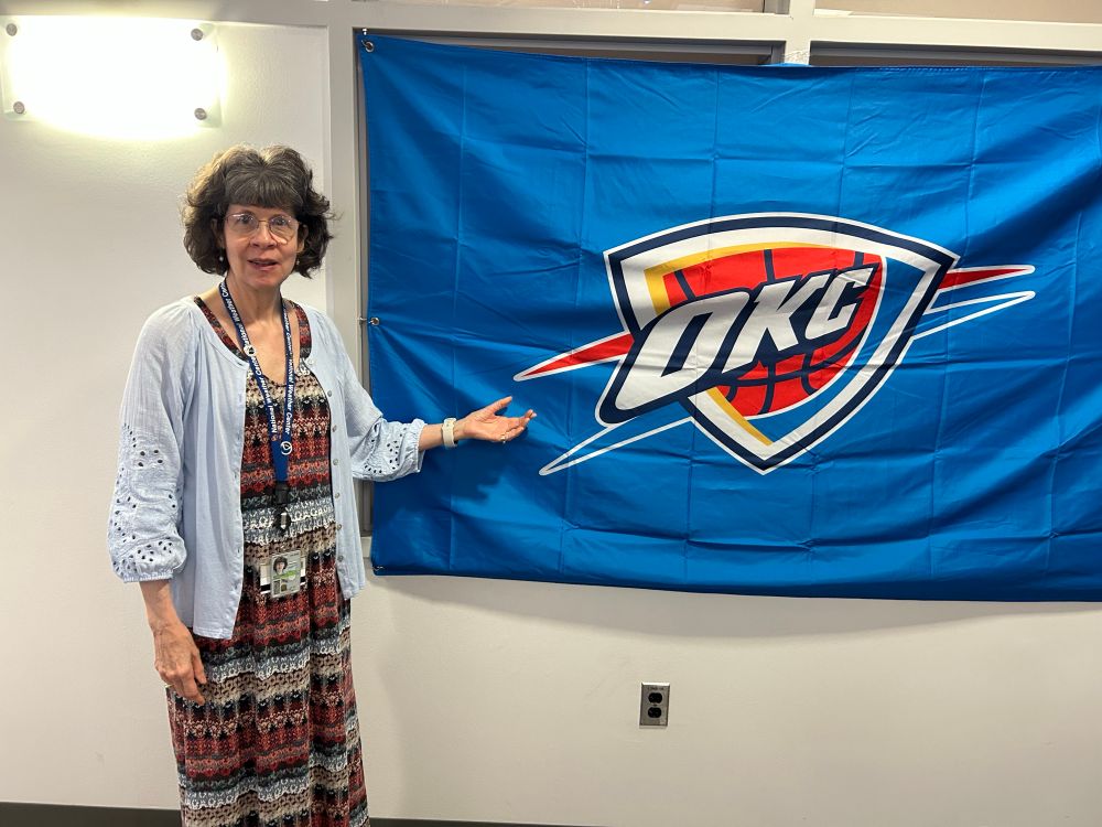 Woman standing in front of an OKC Thunder banner