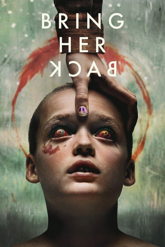 A shaved head child with bulging red eyes staring up and a hand holding the head.