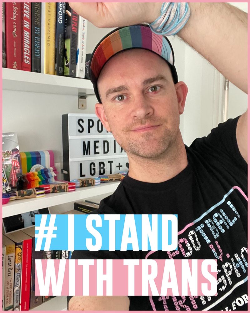 A selfie of Jon in a Football v Transphobia T-shirt and with trans Rainbow Laces tied round his wrist 