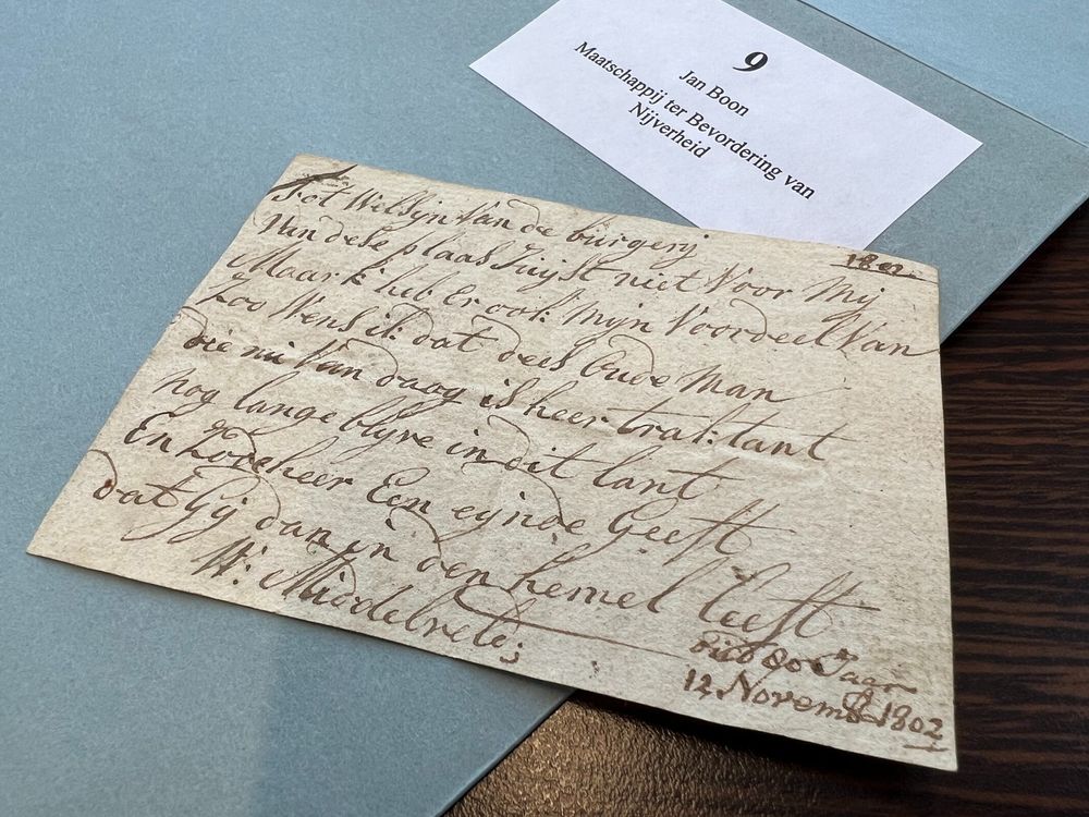 Uit een post van Mariëlle Hageman: een klein briefje met een versje, gelegen op een blauw omslag van inventarisnummer 9 uit het archief van Jan Boon en de Maatschappij ter Bevordering van Nijverheid. Op het briefje de tekst: 
Tot welsijn van de burgerij 
Van dese plaas juijst niet voor mij 
Maar k heb er ook mijn voordeel van 
Zoo wens ik dat dees oude man 
Die nu van daag is heer traktant 
Nog lange blijve in dit lant 
En zo de heer een eijnde geeft 
Dat gij dan in den hemel leeft 
oud 80 Jaar 
12 November 1802 
W. Middelveld
