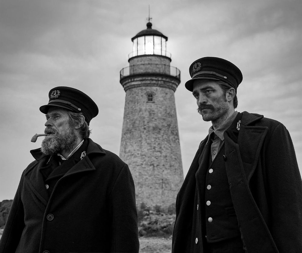 Wake (left) and Winslow (right) stand in front of the lighthouse, looking out to the unseen water