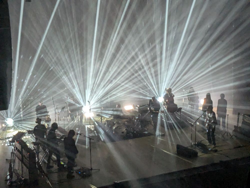 The full band lit by three mirrorballs in a triple starburst effect, of white light this time 