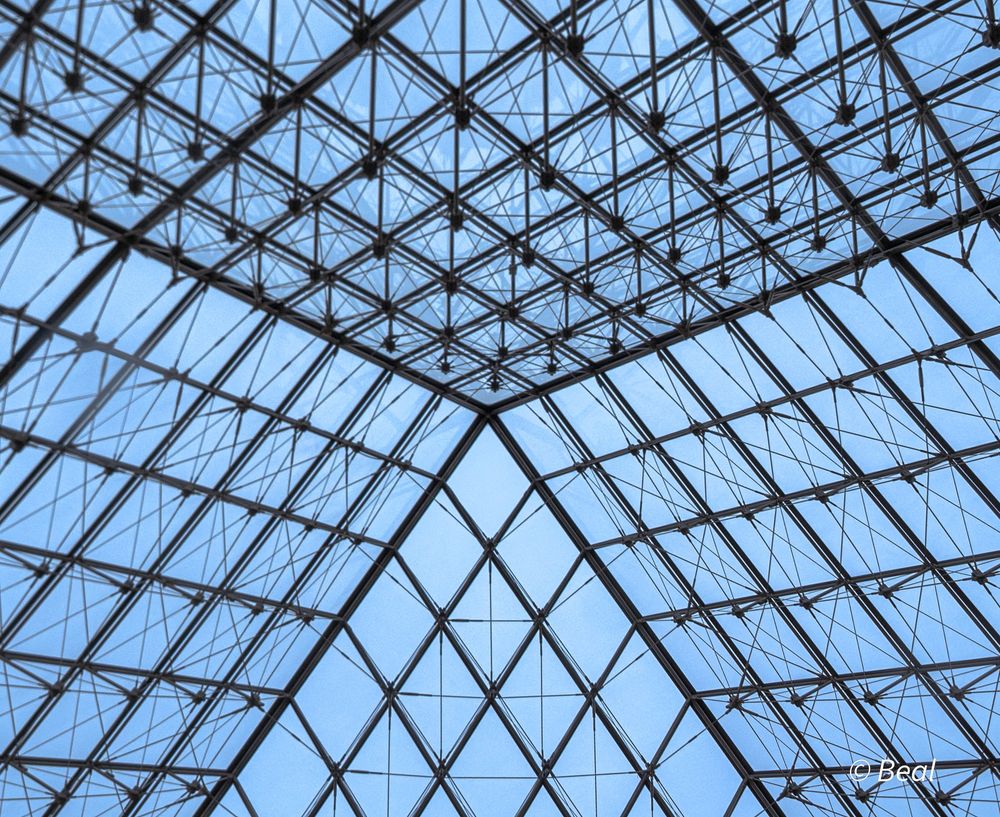 Verrière de la pyramide du Louvre vue de l'intérieur. Un triangle de tuile est au centre.
 
