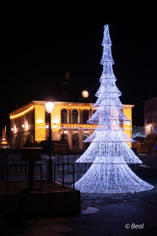 Sapin de Noël fait d'un empilement de cônes formés de guirlandes lumineuses. Photo de nuit.
