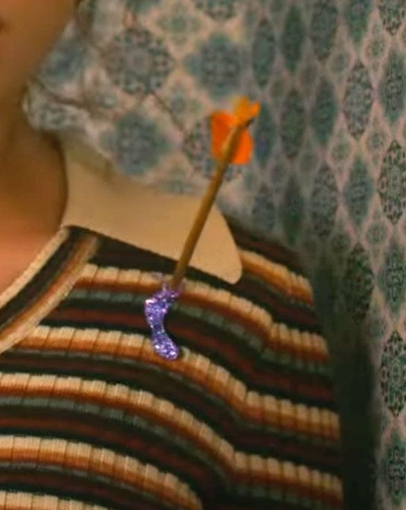 close up of taylor swift in anti hero music video with a small orange arrow on her heart and purple goo 