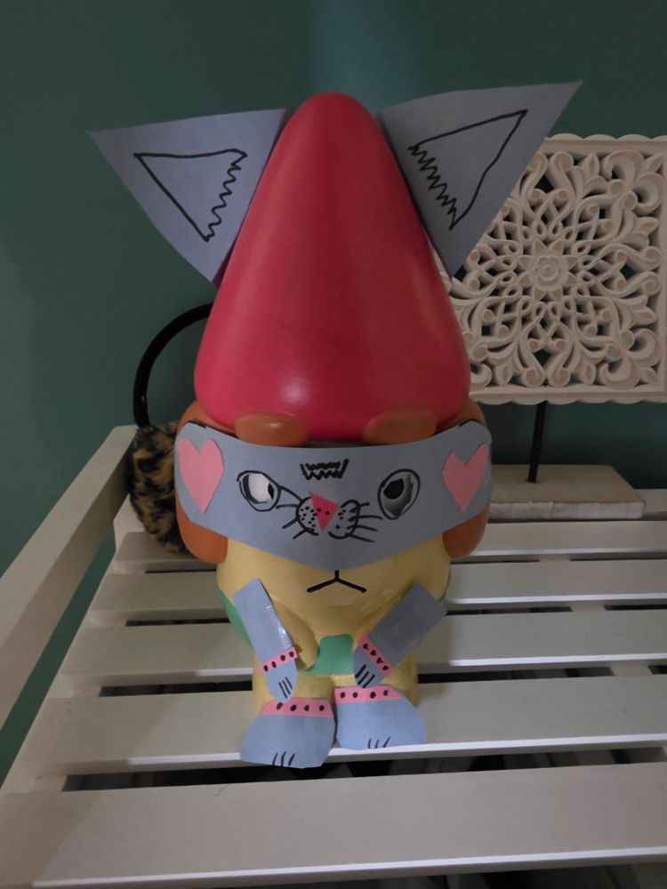 A Bluey garden gnomes with a paper costume on resembling a cat, including arms and legs taped to it