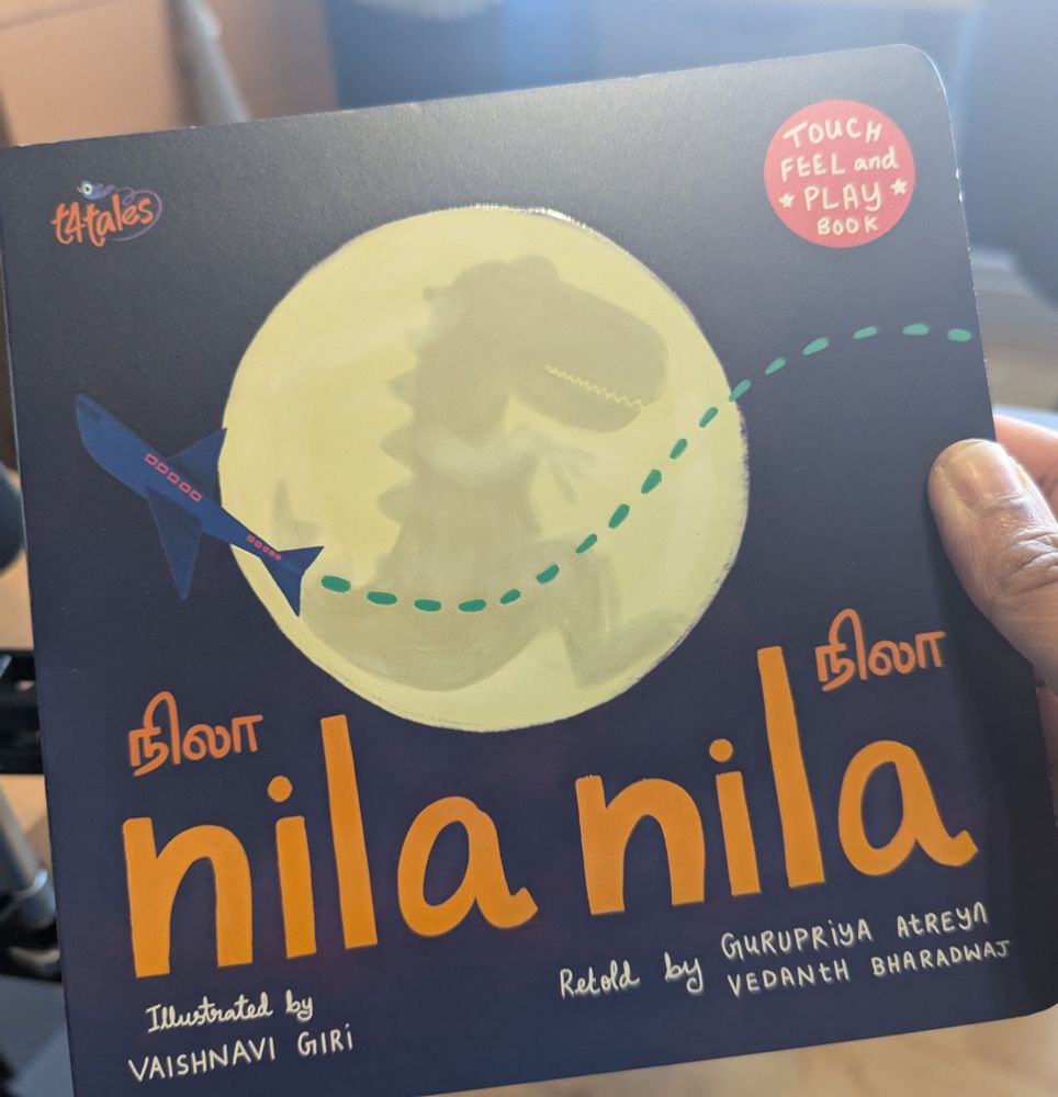 Front cover of a board book with a large graphic moon and an aeroplane. Text says "Nila Nila" in English and in Tamil script.