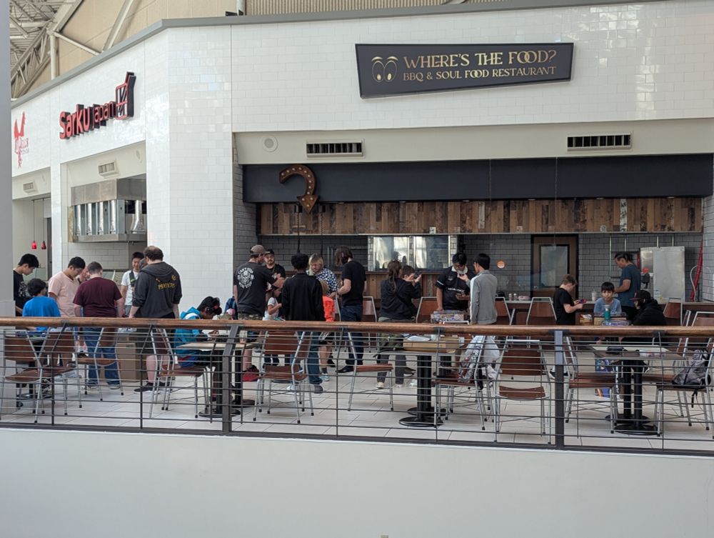 People playing Beyblade in front of an unused food court restaurant.