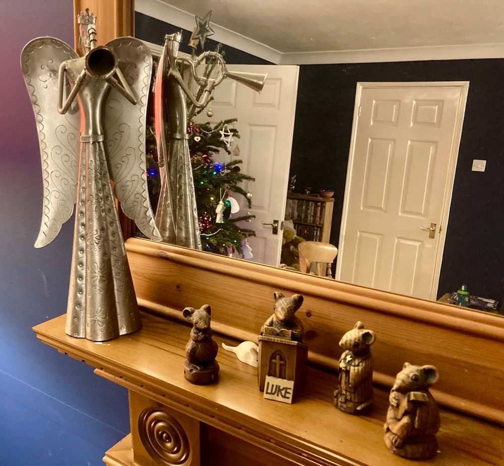 A large metal angel with a trumpet stands above a scene of wooden church mice. The one reading from a lectern is labelled Luke. 