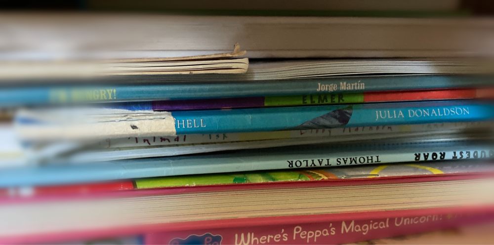 A stack of children’s books. The spine of one by Julia Donaldson is ripped, leaving visible only the partial word ‘HELL’.