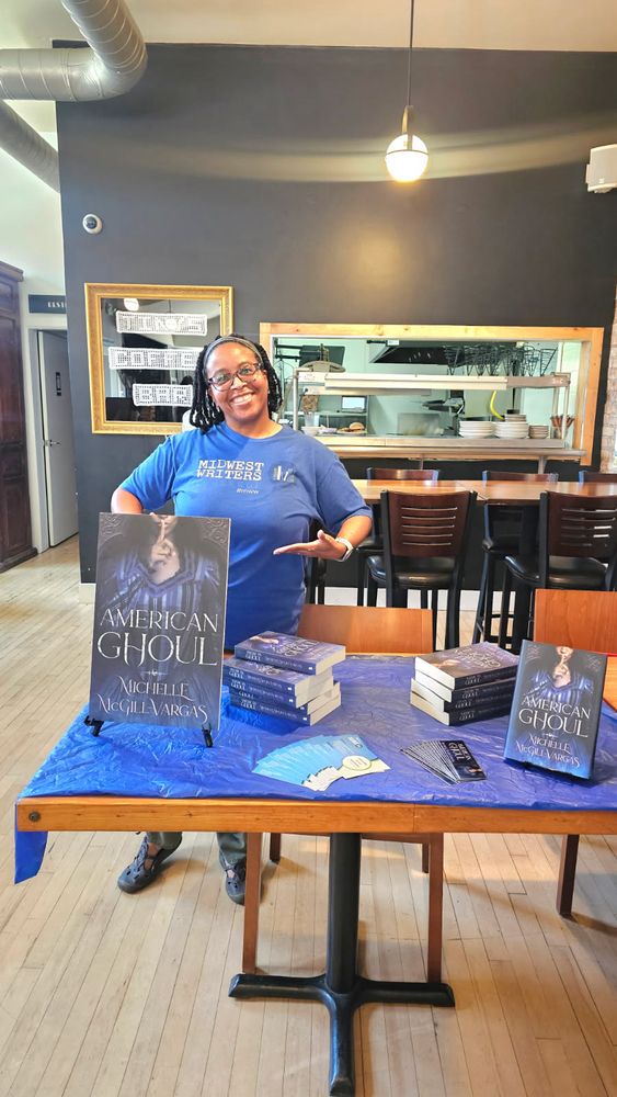 Author standing at table with books in a coffee shop