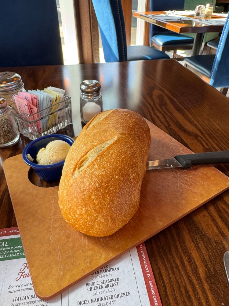 A loaf of bread with butter and a knife