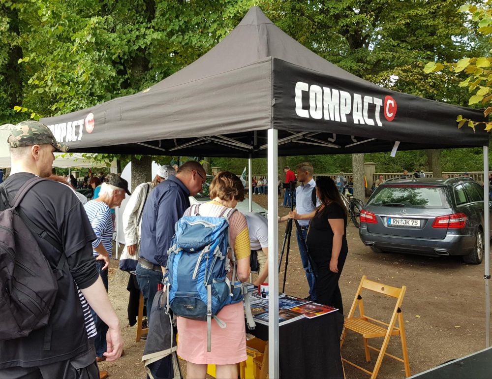 Mehrere Personen an einem Stand des extrem rechten Compact-Magazin.