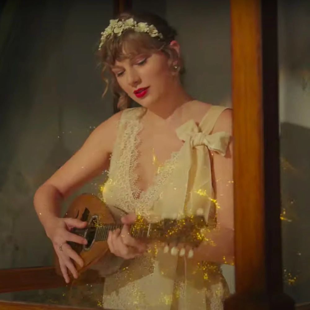 Taylor Swift in a white dress playing the mandolin in the Willow music video
