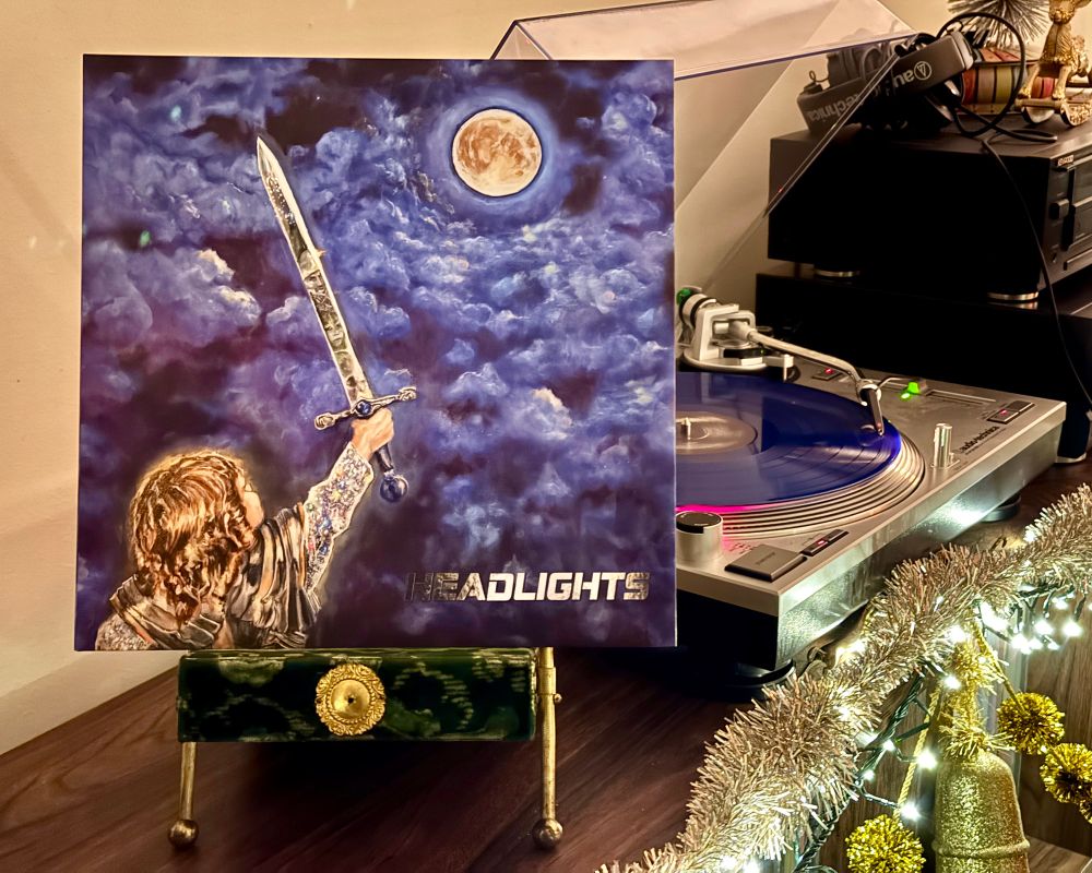 Vinyl copy of Alex G’s album “Headlights” playing on a turntable. The sleeve sits in a velvet Victorian photo stand, which is perched atop a vinyl record shelf decorated for Christmas.

#nowplaying