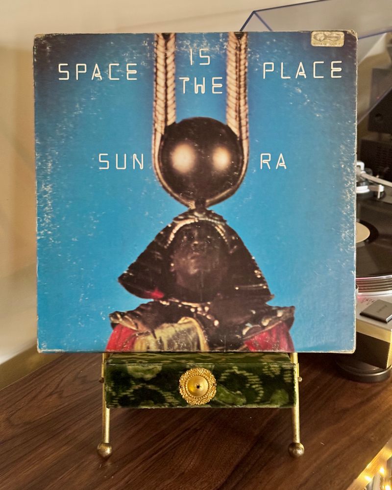 Vinyl copy of Sun Ra’s album “Space Is The Place” sitting in a velvet Victorian photo stand. The record plays on a turntable in the distance.


#nowspinning
#sunra
#freejazz