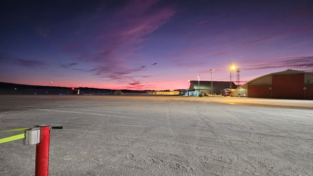 paisagem de gelo com construções aonlonge no horizonte e um céu roxo, azul e rosa
