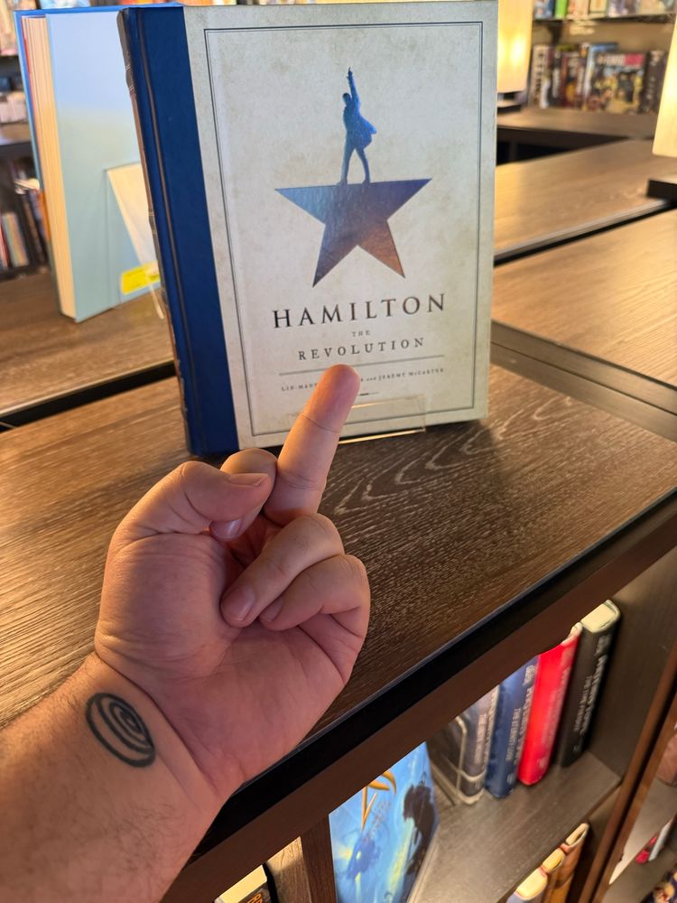 Me flipping off a Hamilton book by Lin Manuel Miranda 