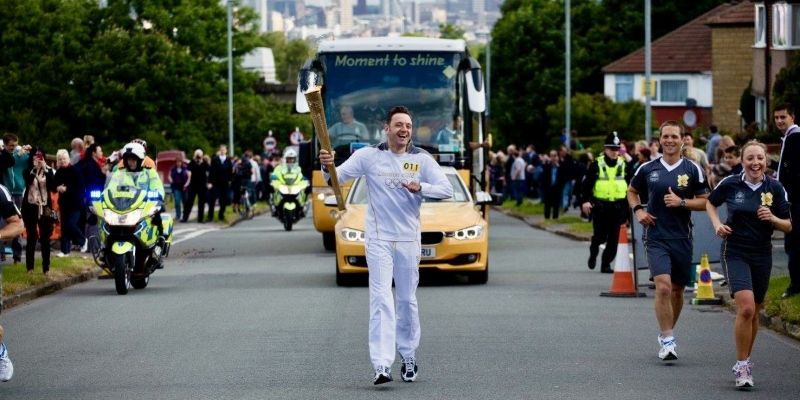 Stewart Ross running holding the Olympic torch 