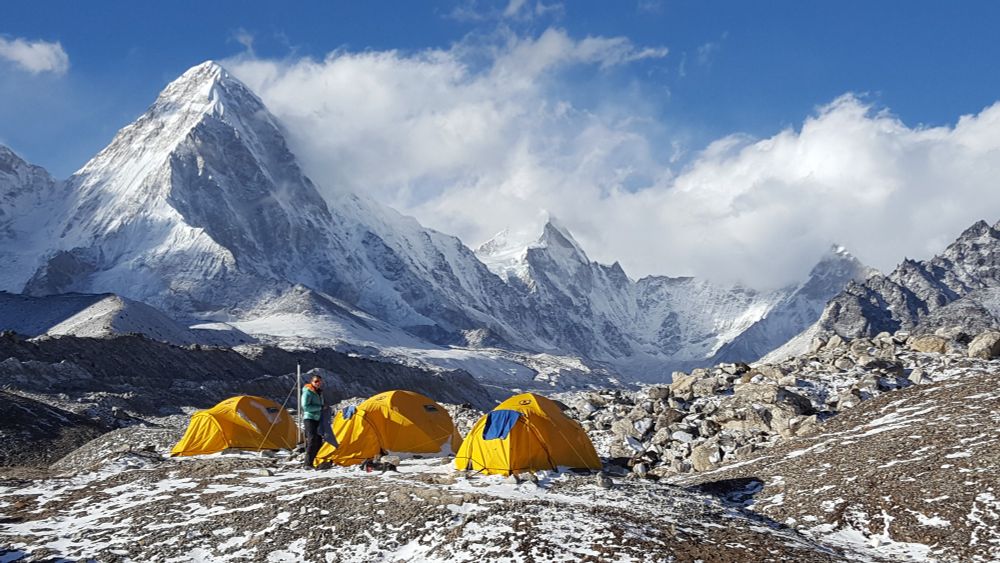 Mount Everest, with tents in the foreground, on a sunny day