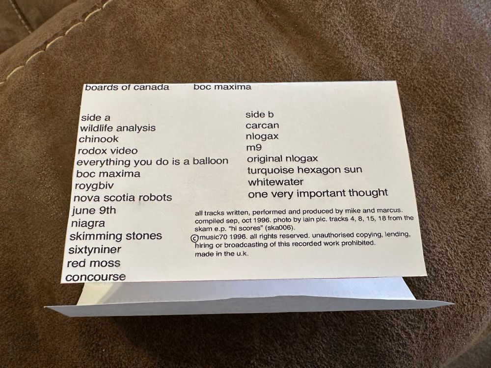 the foldout insert of the j-card, outside the case, showing the track listing and copyright information. the font is still helvetica, with the spacing and stretching varying somewhat (as was the case in the genuine original version of the tape). it reads:

boards of canada      boc maxima

side a
wildlife analysis
chinook
rodox video
everything you do is a balloon
boc maxima
roygbiv
nova scotia robots
june 9th
niagra
skimming stones
sixtyniner
red moss
concourse

side b
carcan
nlogax
m9
original nlogax
turquoise hexagon sun
whitewater
one very important thought

all tracks written, performed and produced by mike and marcus.
compiled sep, oct 1996. photo by iain pic. tracks 4, 8, 15, 18 from the skam e.p. "hi scores" (ska006).
[hand drawn copyright symbol] music70 1996. all rights reserved. unauthorised copying, lending, hiring or broadcasting of this recorded work prohibited.
made in the u.k.
