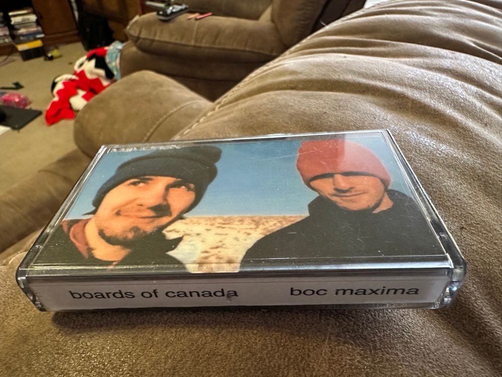 a view showing both the front and side of the cassette case, with the image described in the previous picture on the front, and on the side, the text "boards of canada     boc maxima" in a stretched helvetica font.