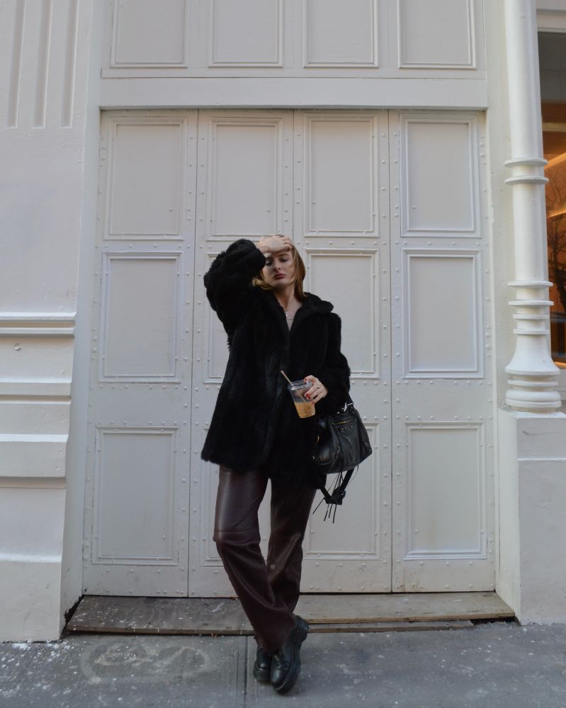 a blonde woman in a fur coat and leather pants.